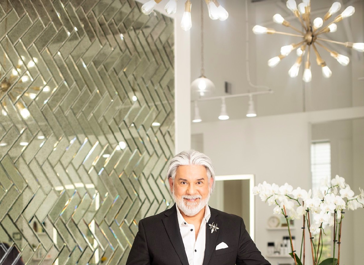 Wide view of the salon — herringbone mirror wall, sputnik chandelier, and the master himself