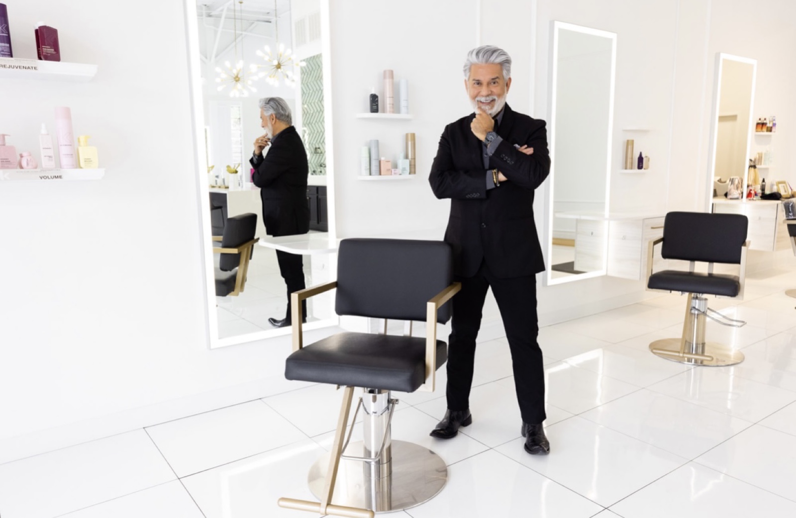 Charles at his styling station — gold-rim chair, full-length mirrors, product shelves